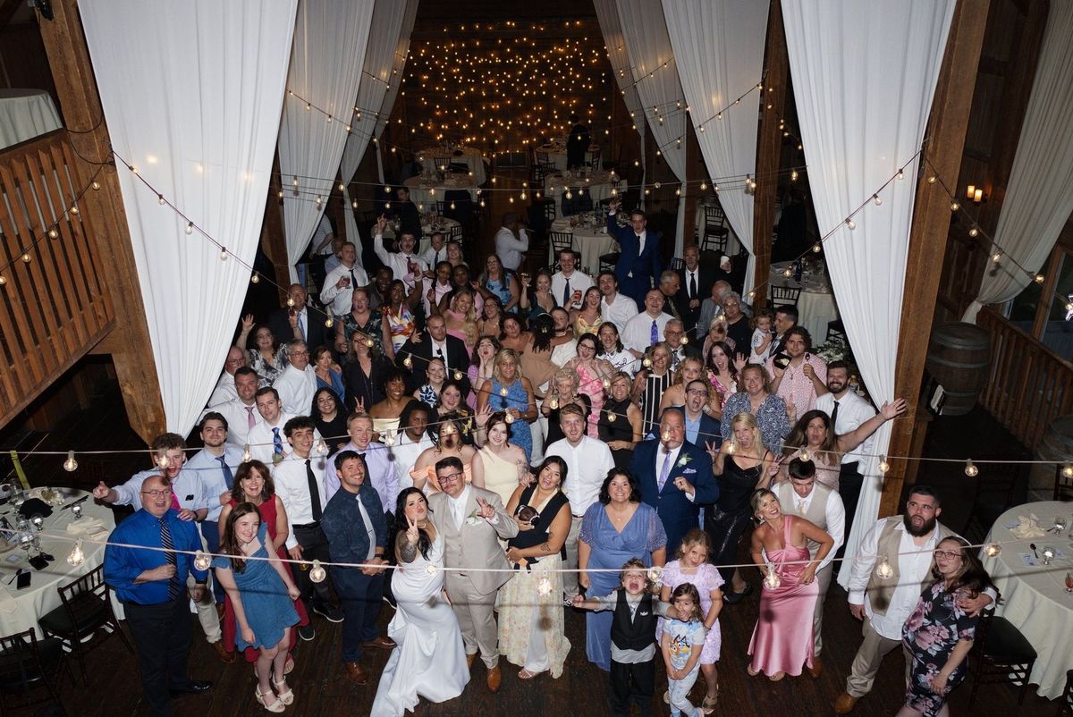 Sadie and Mat celebrate with their guests in a group photograph inside the barn