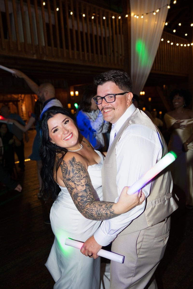 Sadie and Mat smile together with glow sticks on the dance floor