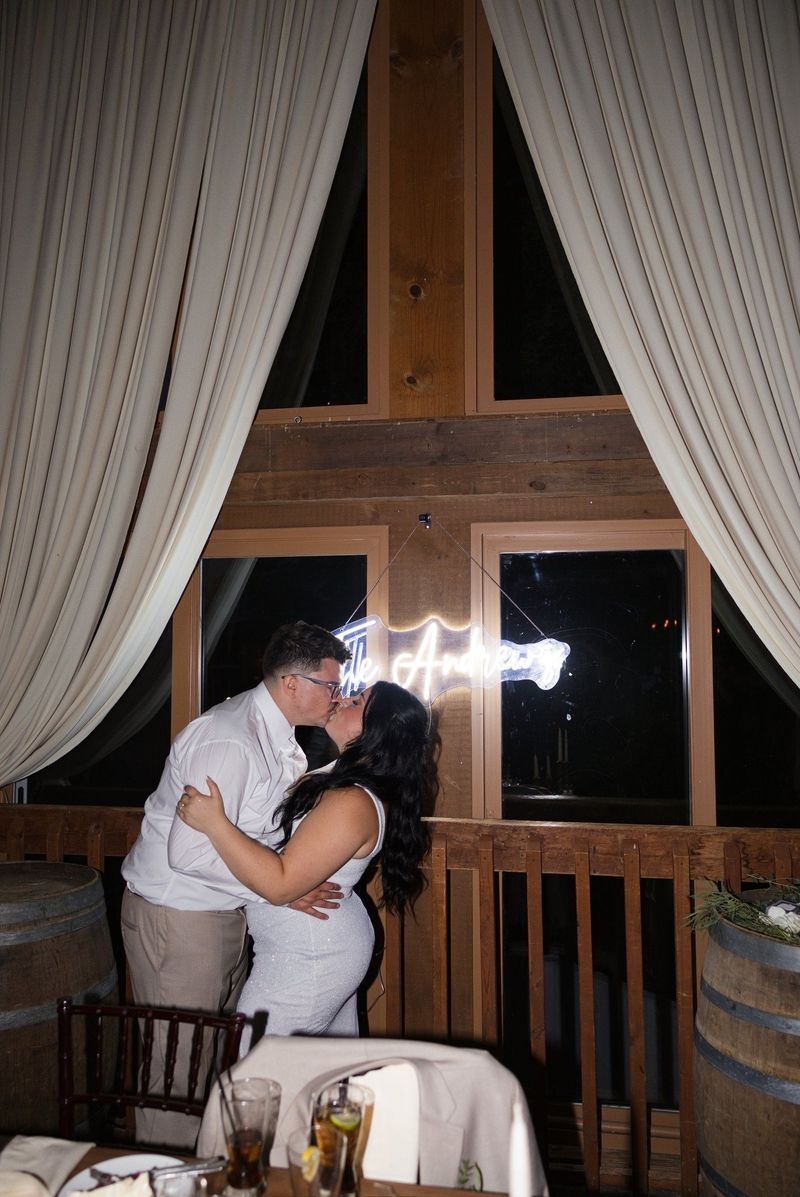 Sadie and Mat kiss beneath their illuminated Andrews sign at night