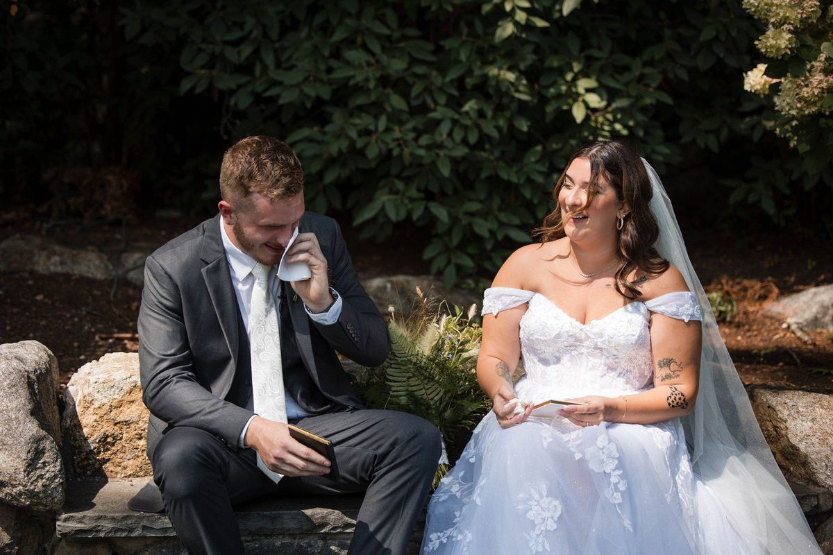 Tommy wipes his eye while sitting beside Sophia with written pages in the garden