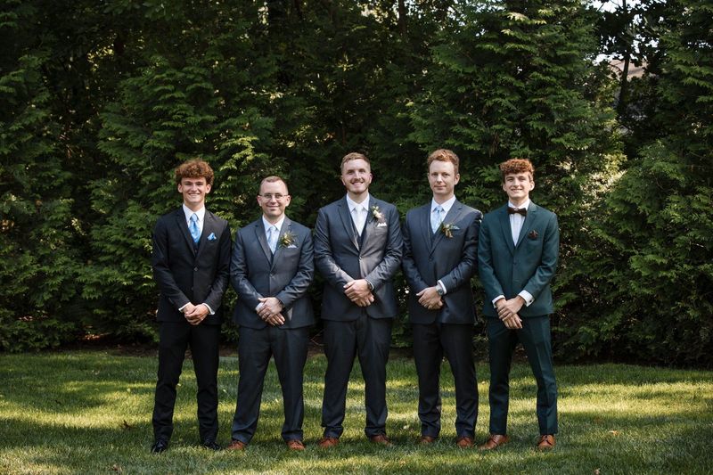 Tommy stands with the groomsmen in a coordinated garden group portrait