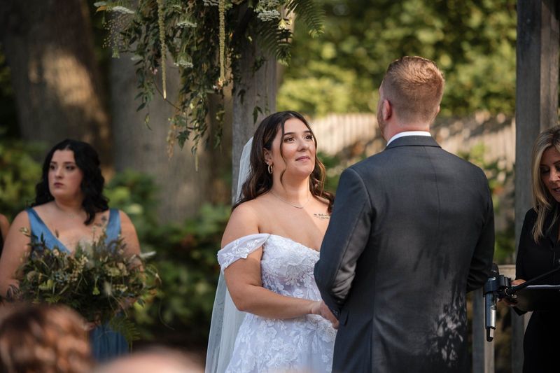 Sophia watches Tommy with a soft smile during their garden ceremony