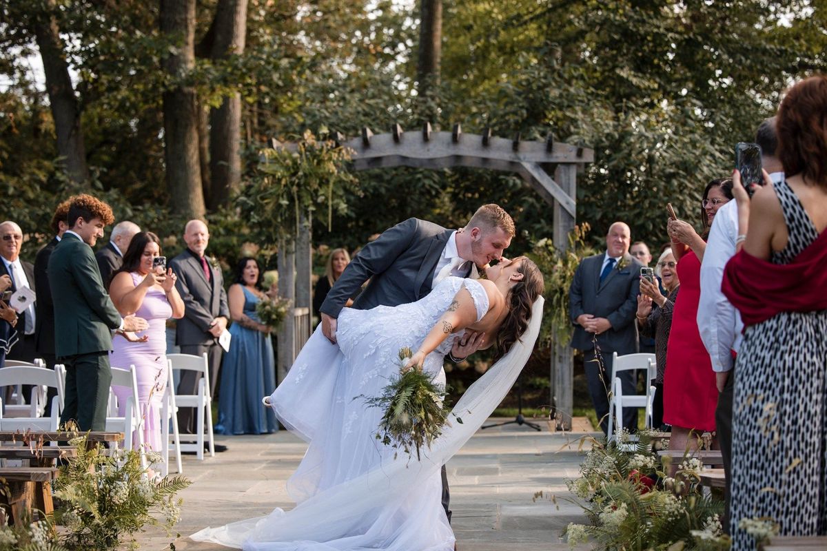 Tommy dips Sophia for a kiss in the aisle while their guests watch