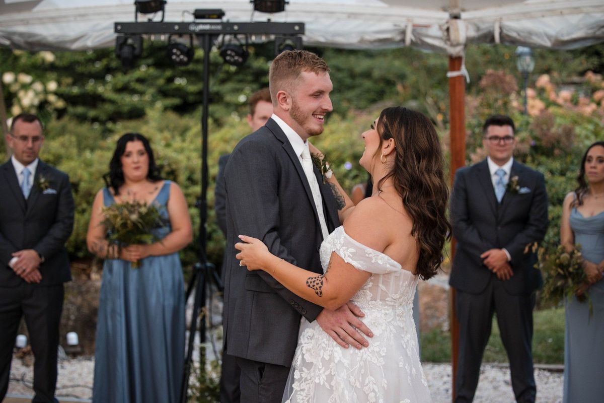 Sophia and Tommy smile toward each other while dancing beneath the reception tent