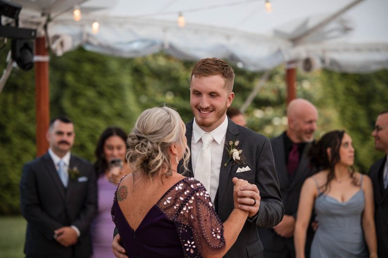 Tommy smiles while dancing with a guest beneath the reception tent