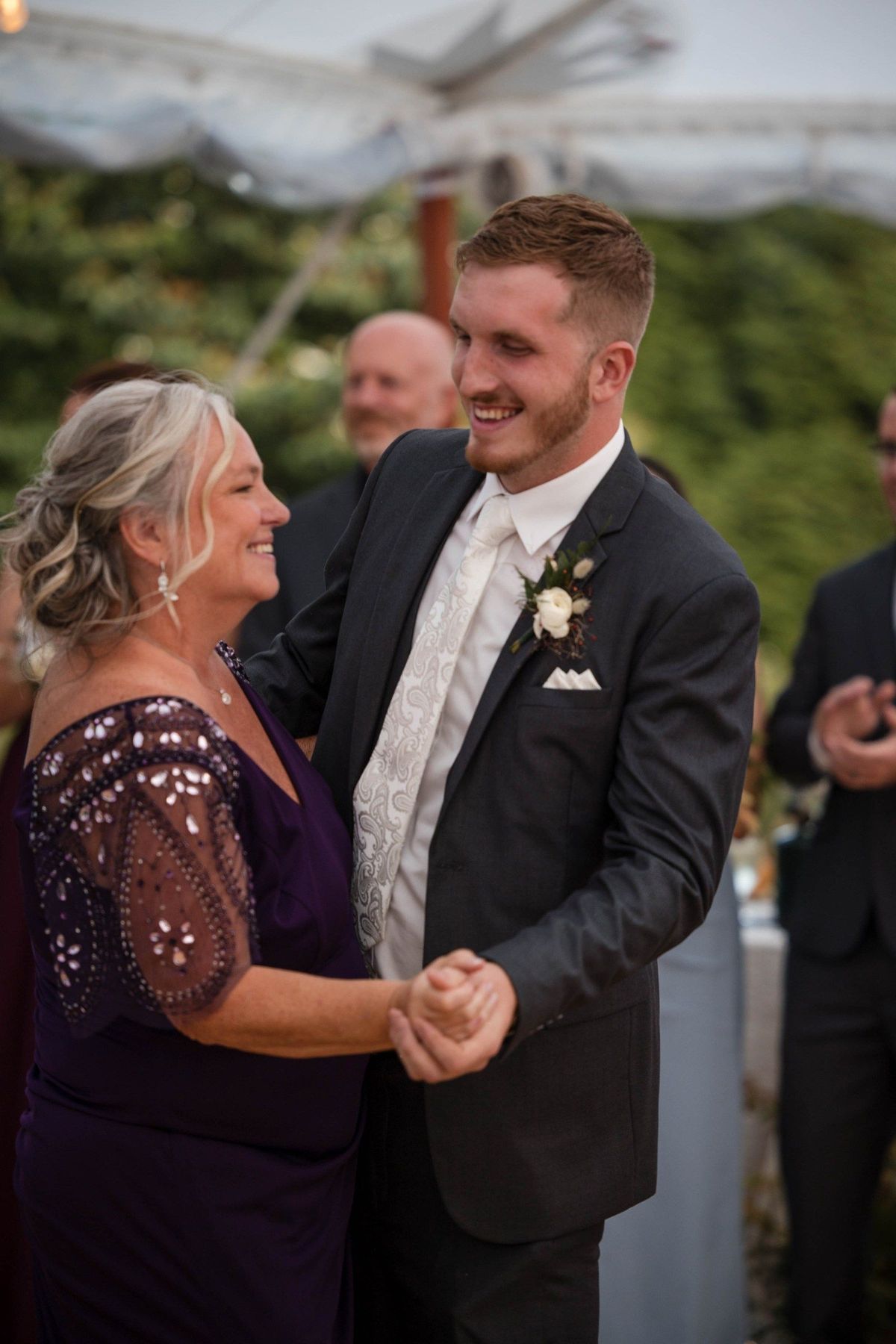 Tommy dances with a smiling guest in a purple dress under the tent