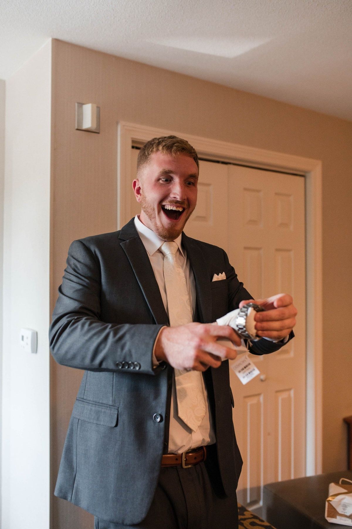 Tommy reacts with a wide smile while opening a small box
