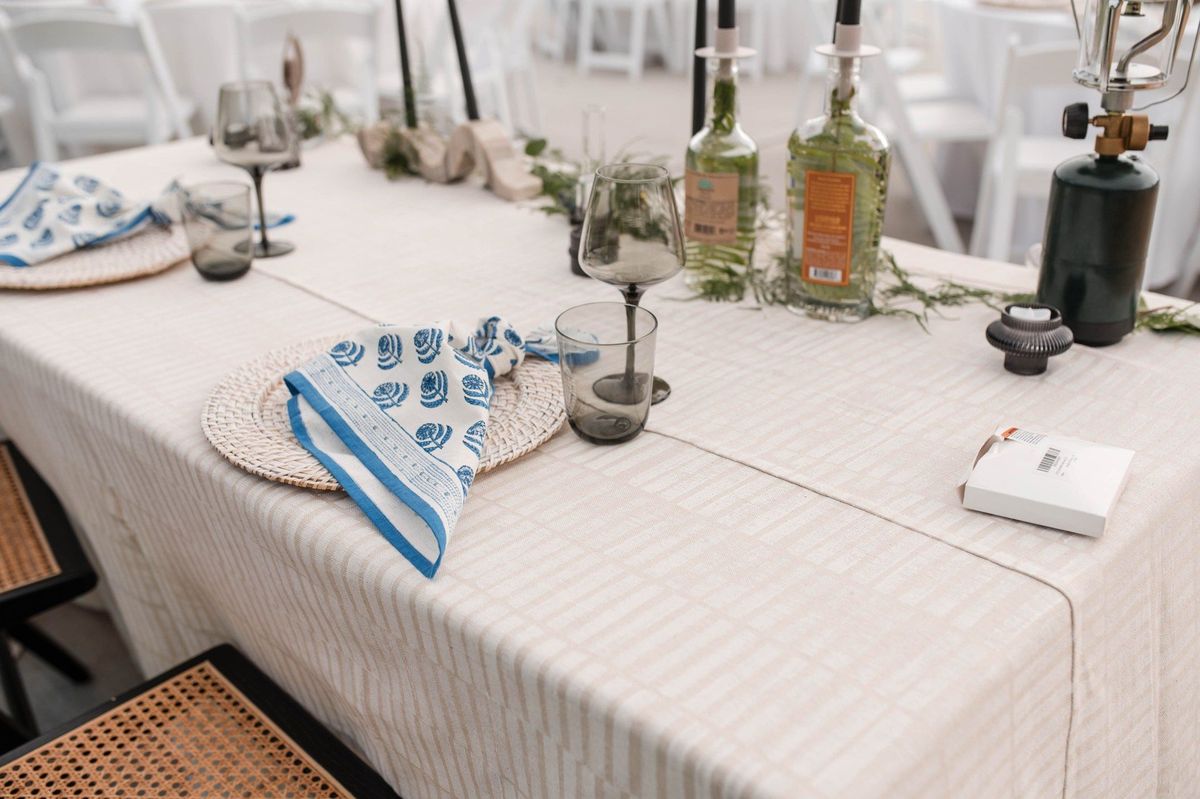 Blue and white napkins and floral arrangements decorate a reception table beneath the tent