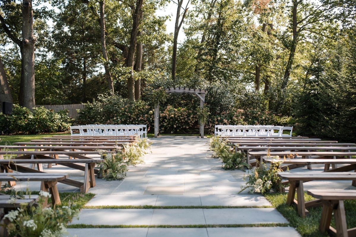 Rows of benches and chairs lead toward the empty garden ceremony arbor
