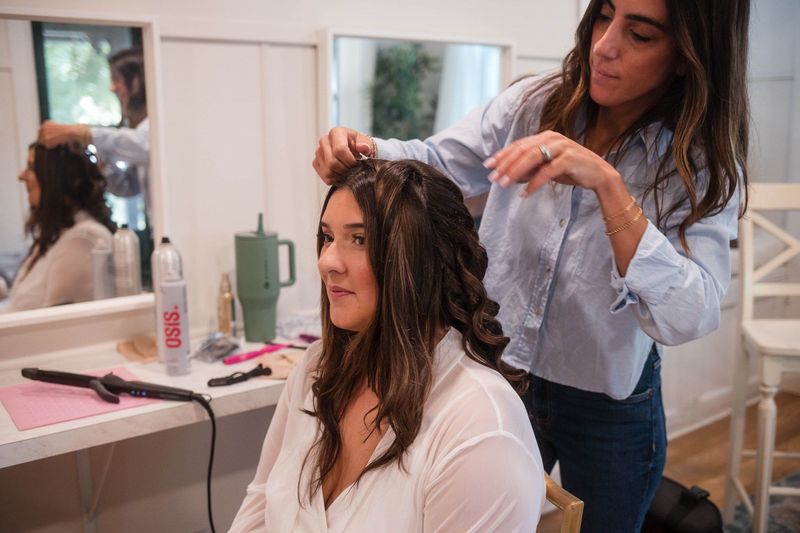 A stylist works on Sophia’s hair in front of a mirror