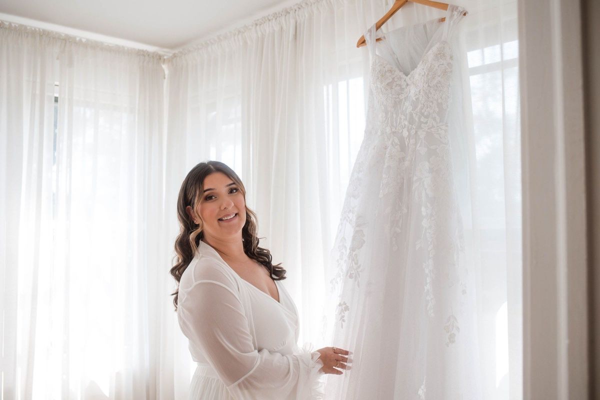 Sophia smiles beside her hanging wedding dress before getting ready