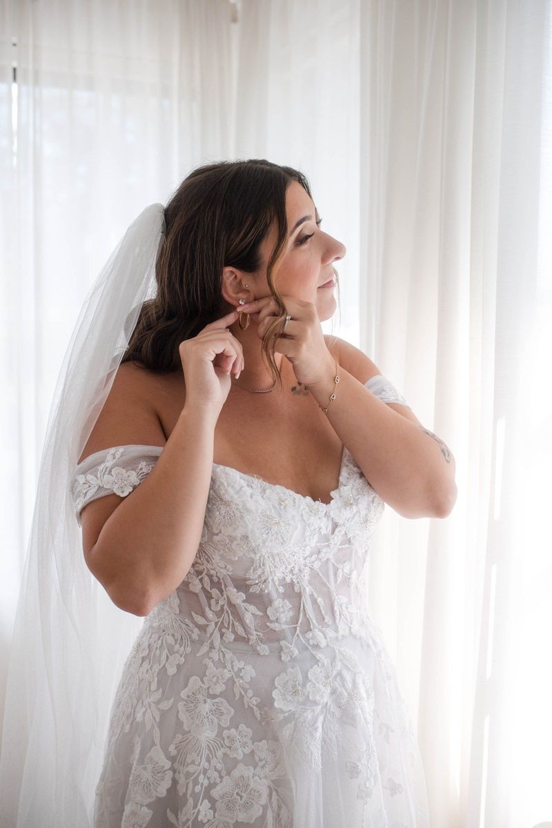 Sophia adjusts an earring beside a softly lit window