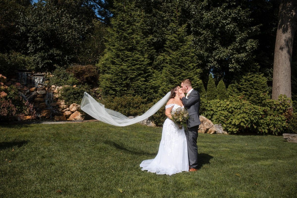 Sophia’s veil floats to the side as the couple embrace on the garden lawn