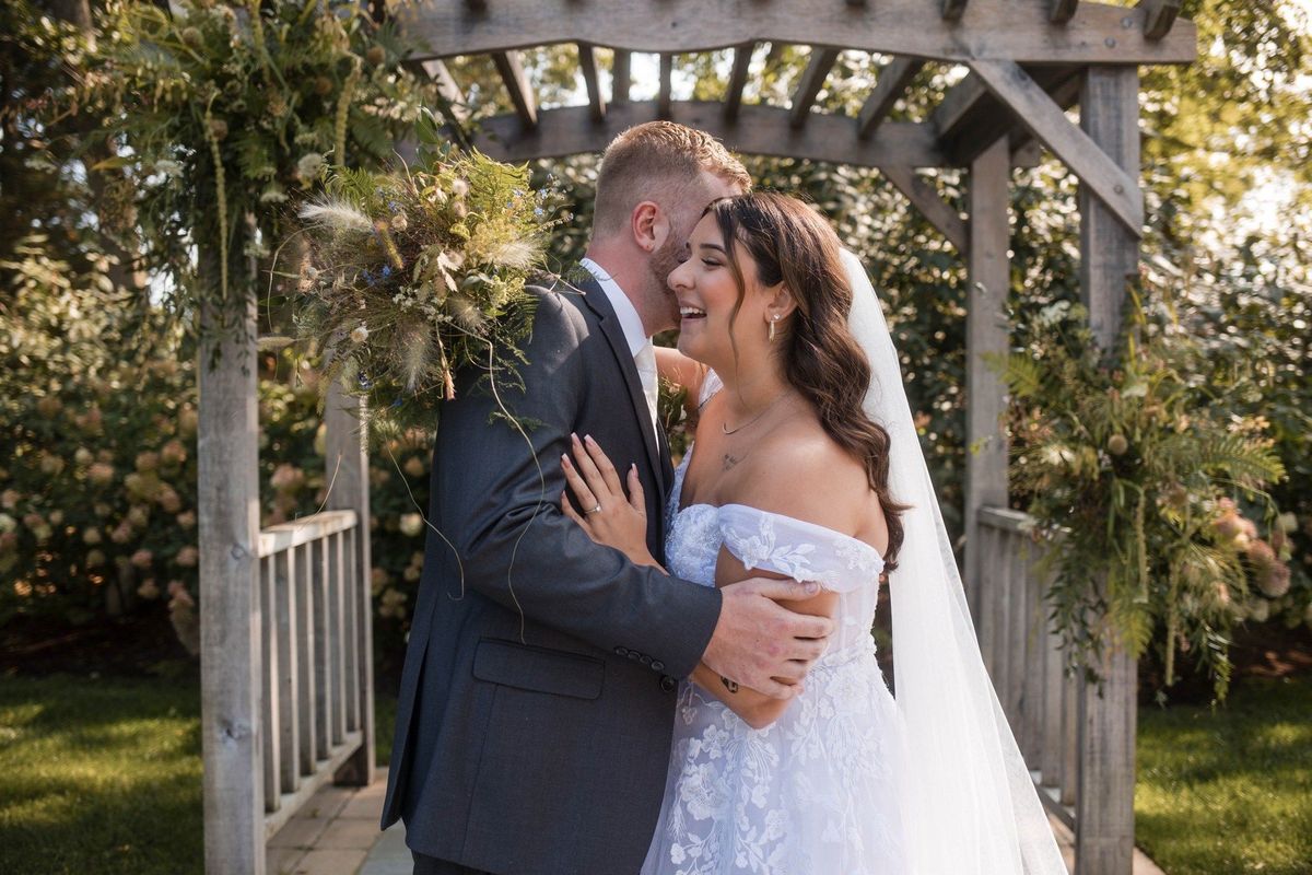 Sophia smiles as Tommy kisses her forehead beneath the garden arbor