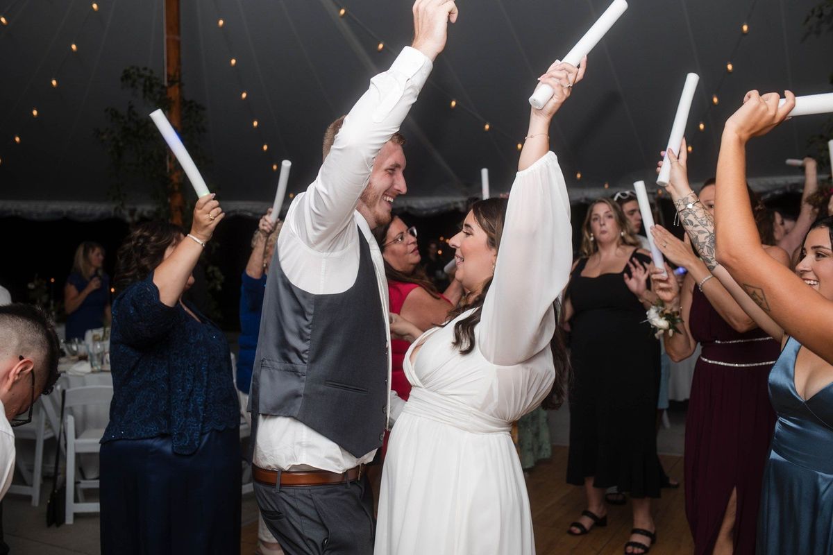 Sophia and Tommy raise glowing foam sticks while dancing with guests at night