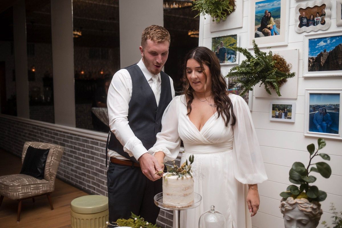 Sophia and Tommy cut their floral wedding cake together indoors