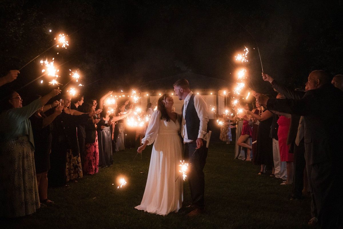 Sophia and Tommy kiss between two rows of guests holding sparklers