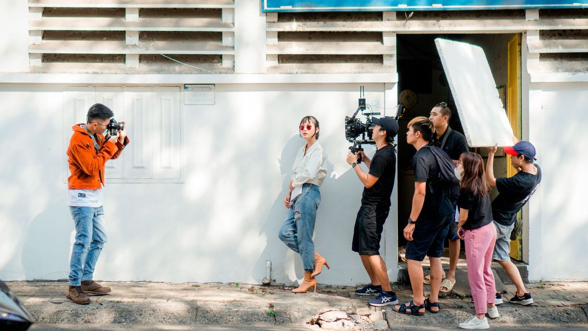A video crew shooting a model with a reflector in bright light