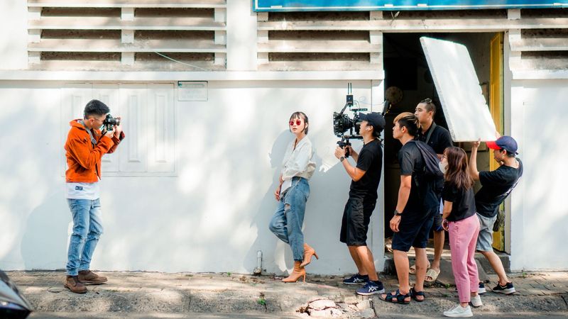 A video crew shooting a model with a reflector in bright light