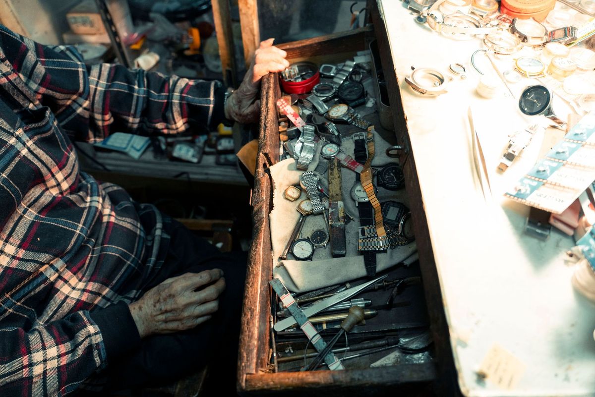 An elderly man working at a bench in a workshop