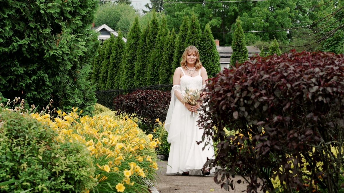 Sara stands with her bouquet in the garden