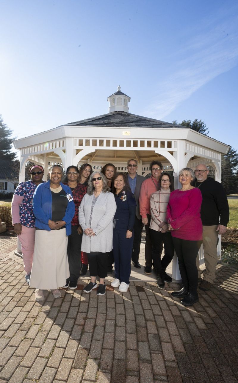 Team group portrait outdoors in front of a white gazebo