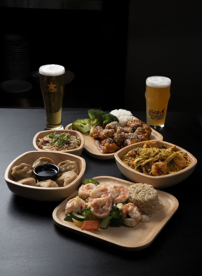 Plated dishes and two tall drinks against a dark background