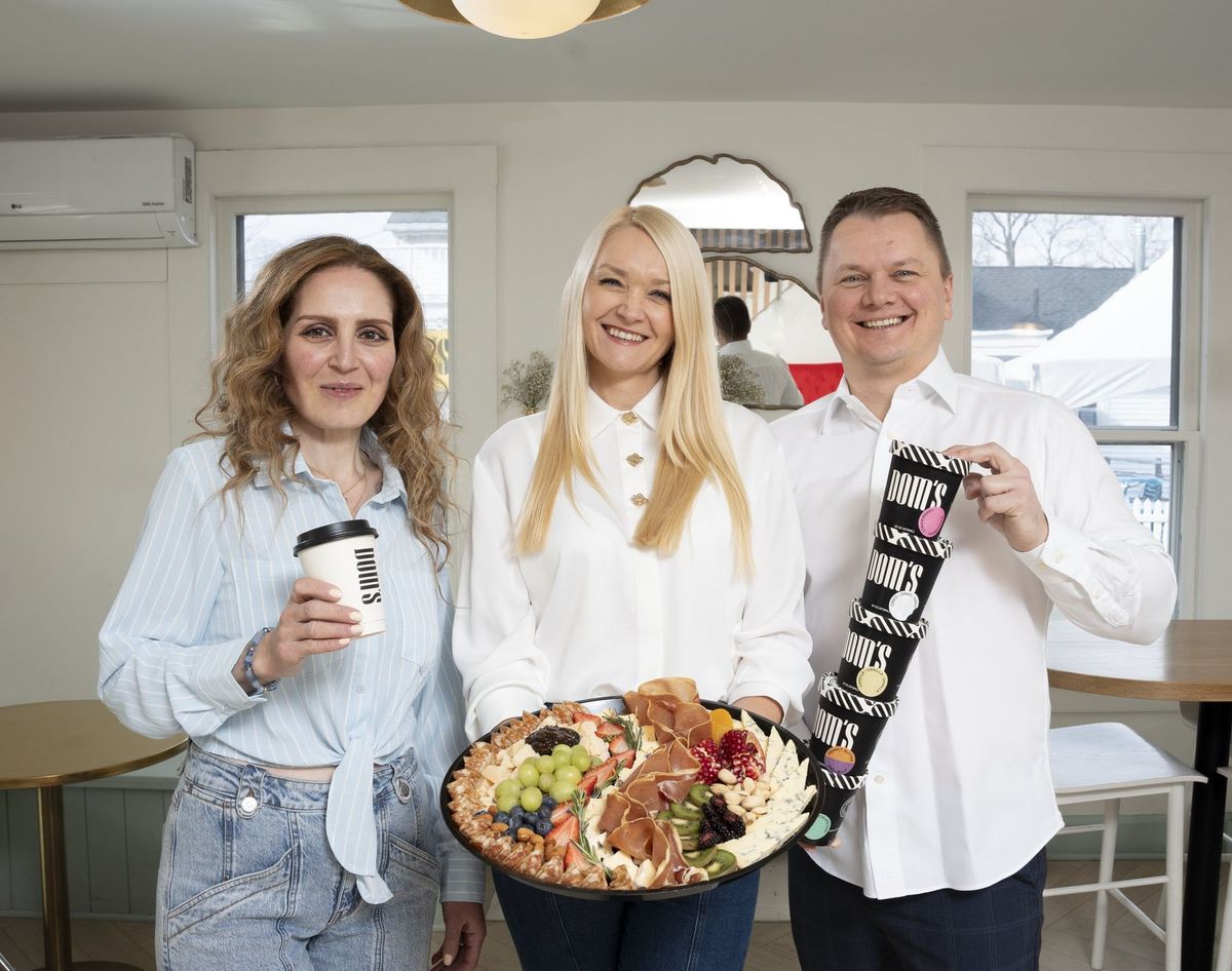 Closer group portrait of three people holding drinks and a food platter