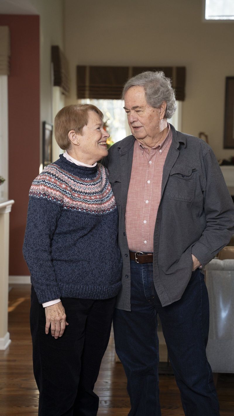 Two older adults standing close together and looking toward one another