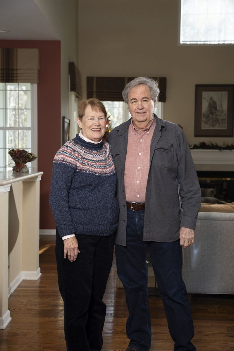 Two older adults smiling together in a home interior