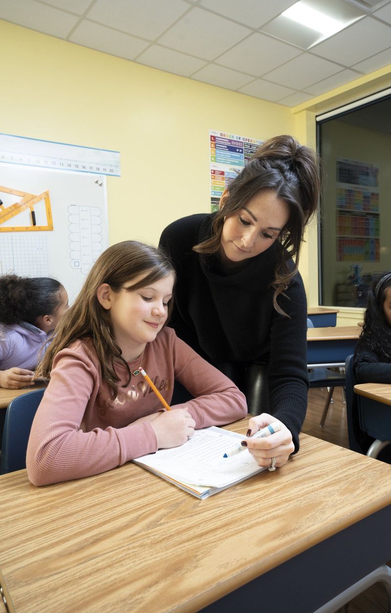 Teacher leaning beside a student working at her desk