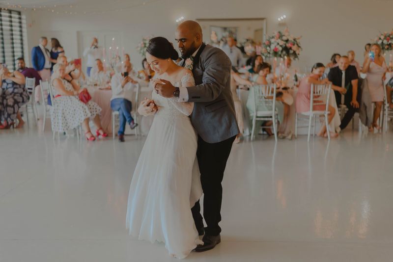A bride and groom sharing a dance on a bright floor while seated guests watch from decorated tables