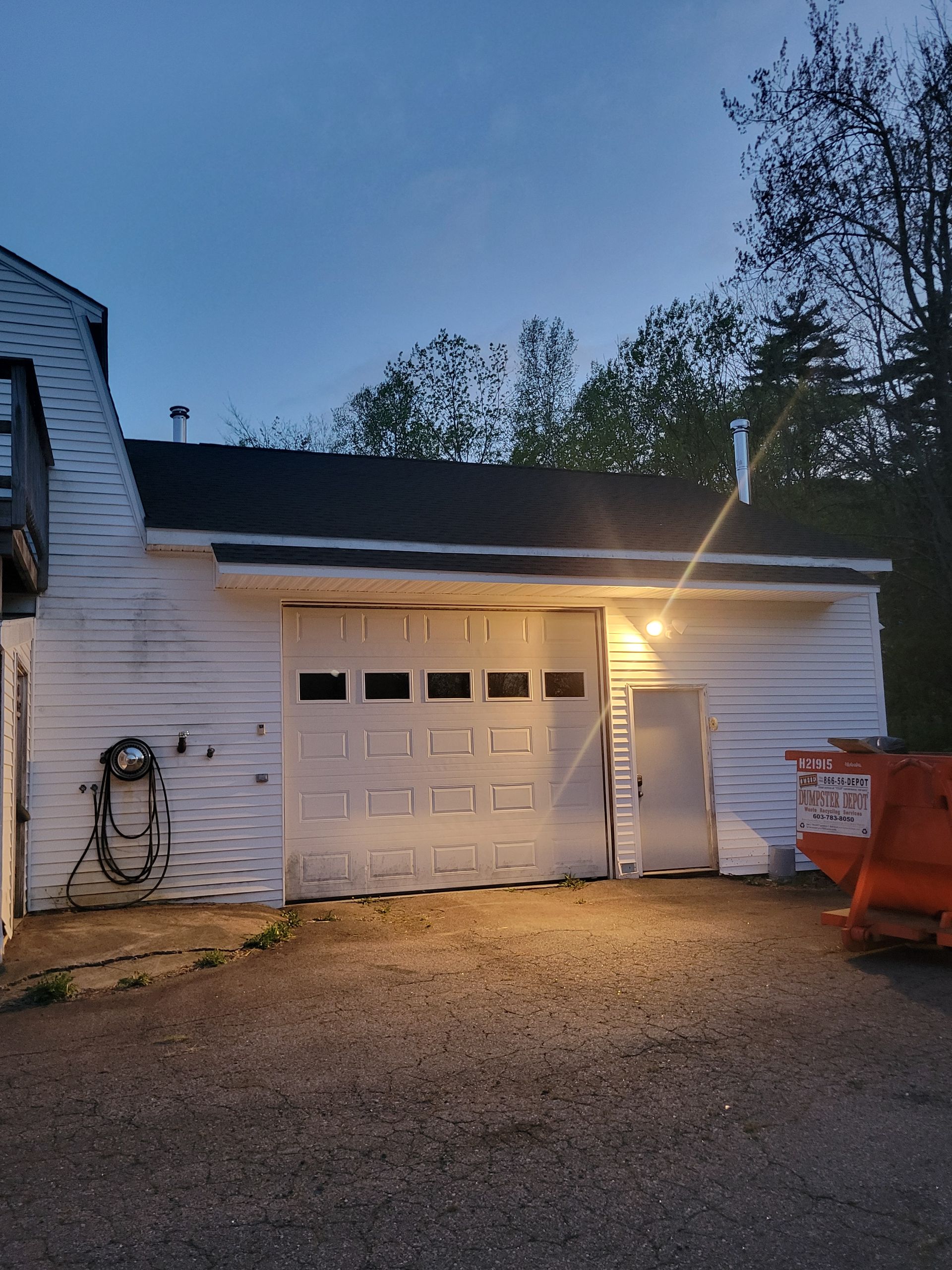 A white garage with a black roof is lit up at night