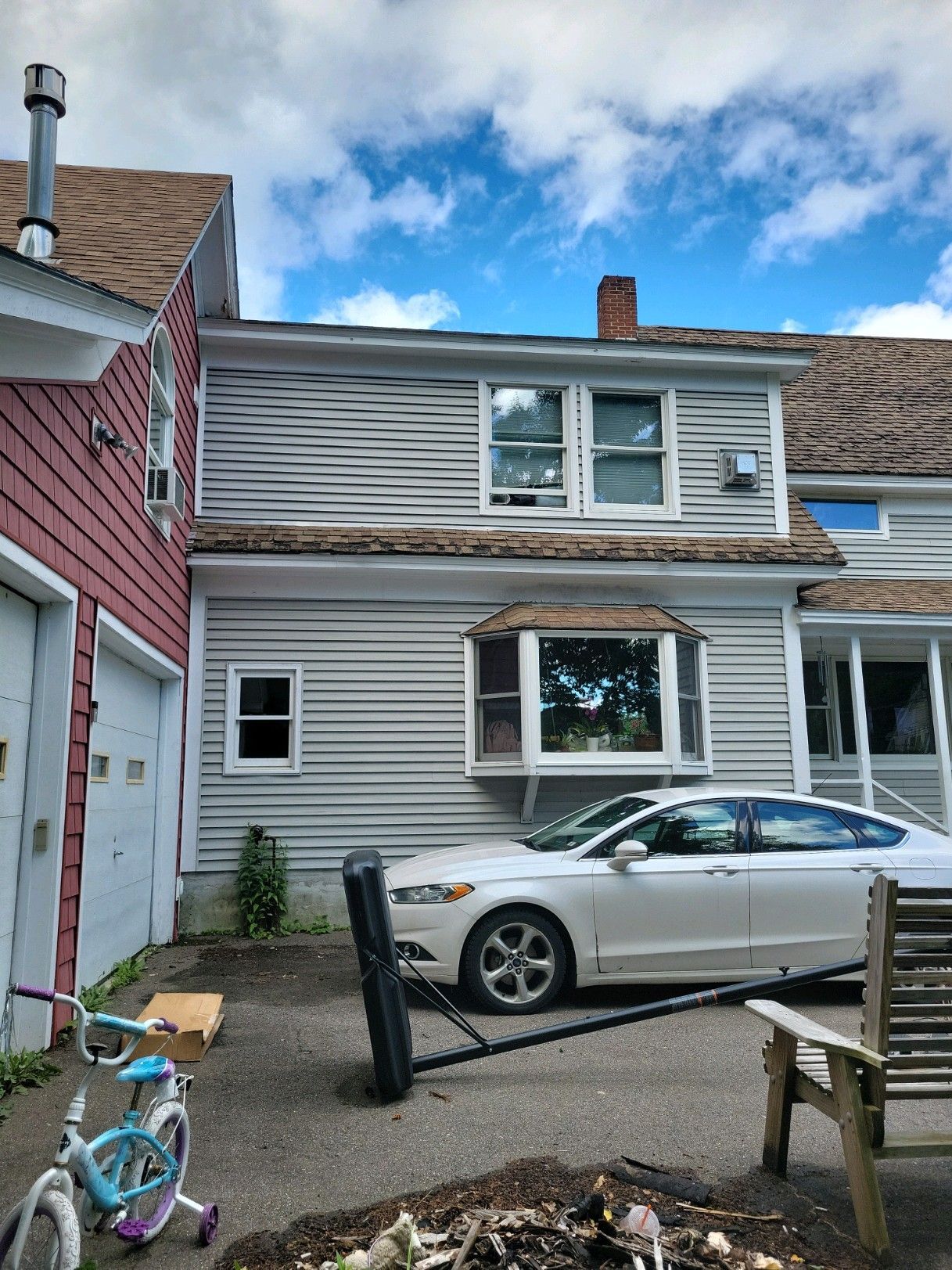 A white car is parked in front of a house.