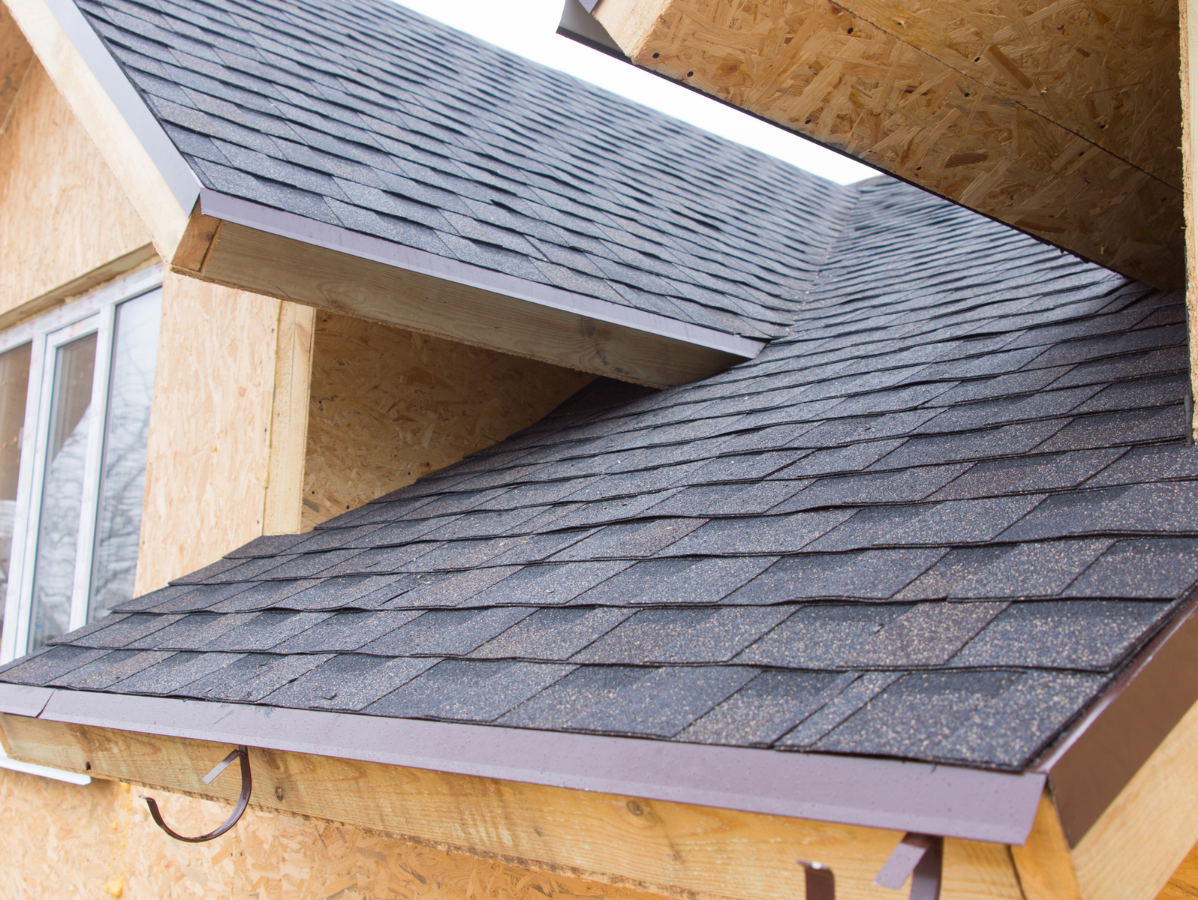Shingled roof sections meeting at a corner on a house under construction