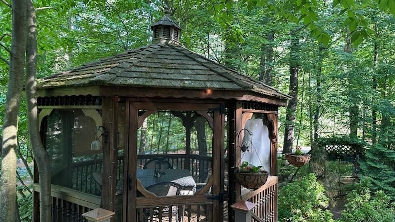 A gazebo is sitting in the middle of a forest surrounded by trees.