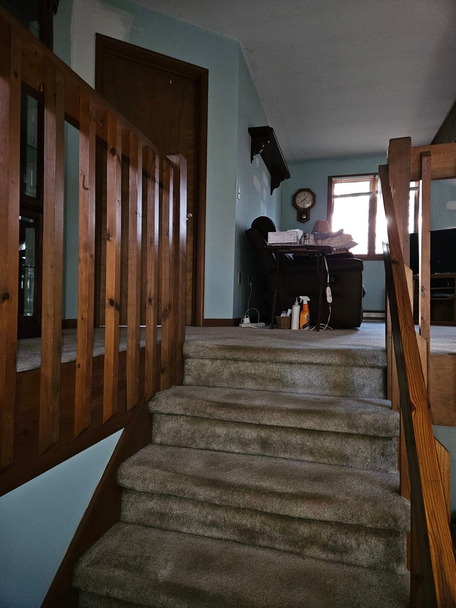 Carpeted stairs leading to an upstairs hallway with wooden railings and a desk at the top.