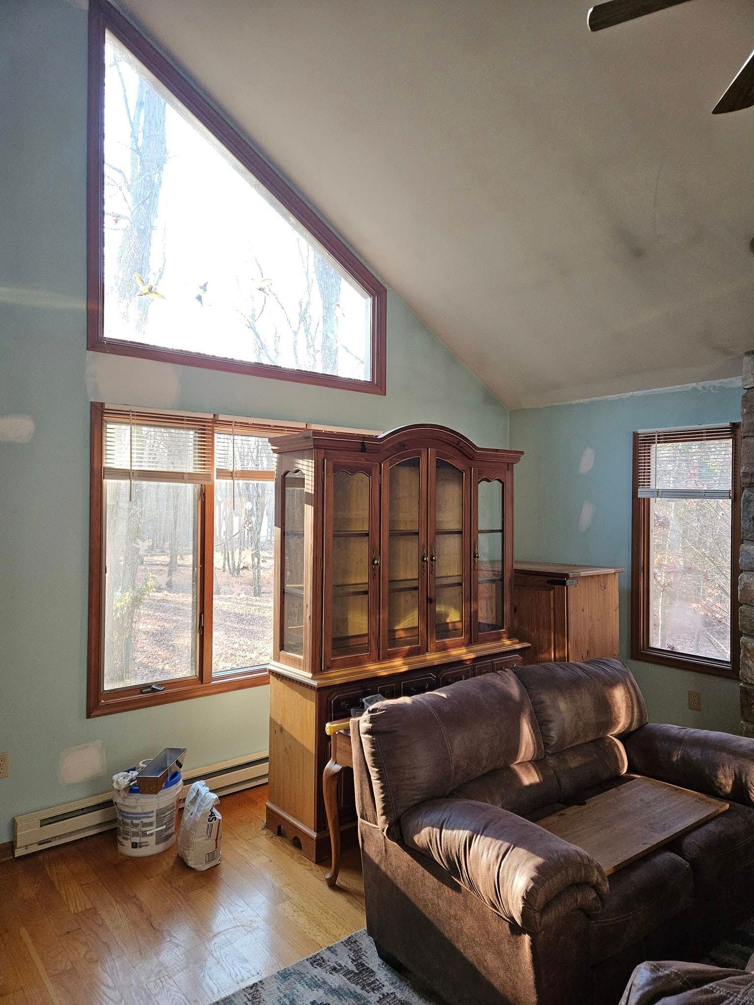 Living room with leather sofa, wood hutch, and large windows letting in bright daylight