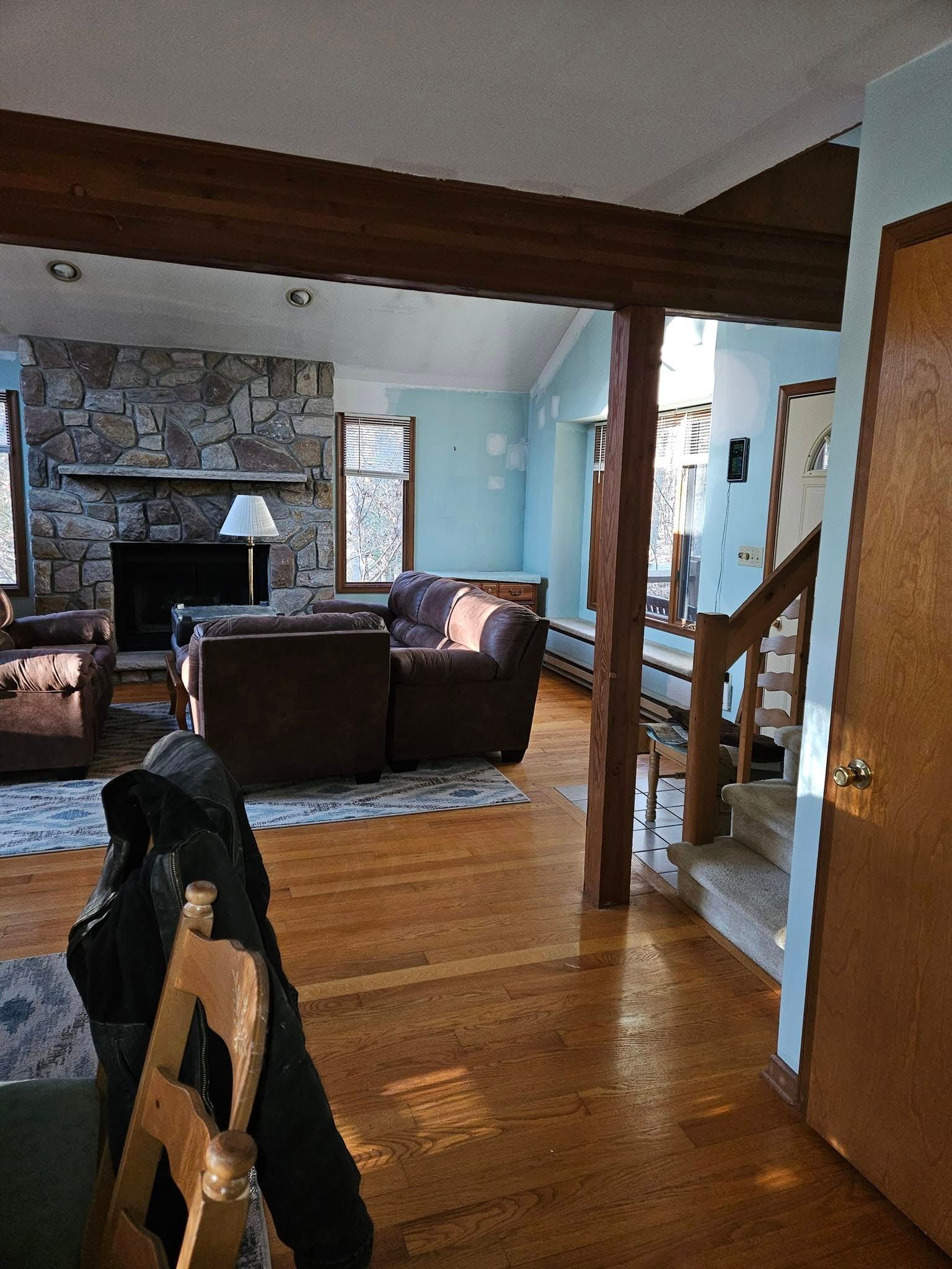 Living room with hardwood floors, sofa, fireplace, and a black cat on a chair in the foreground
