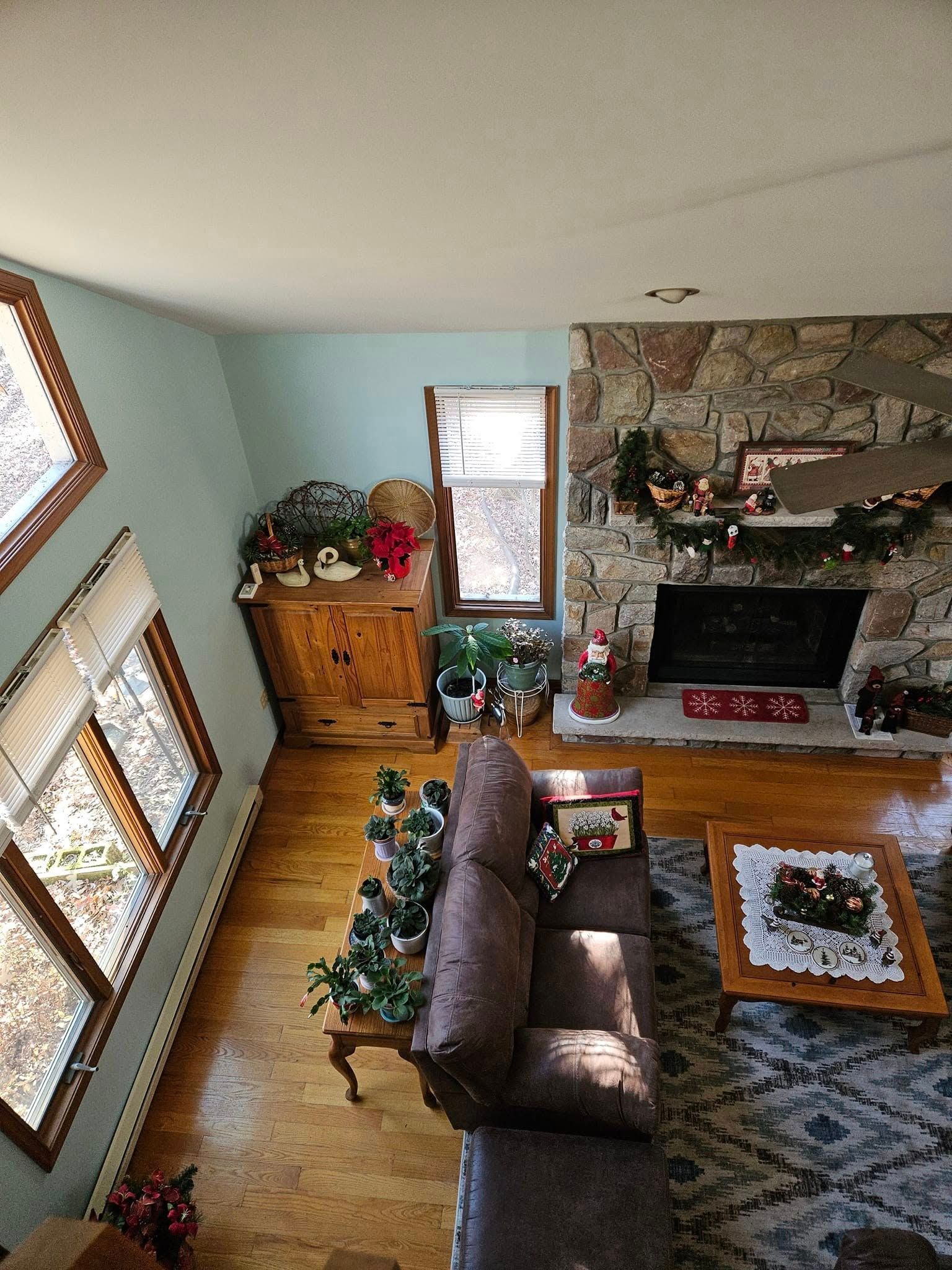 Living room with leather sofa, stone fireplace, patterned rug, and large windows bringing in daylight