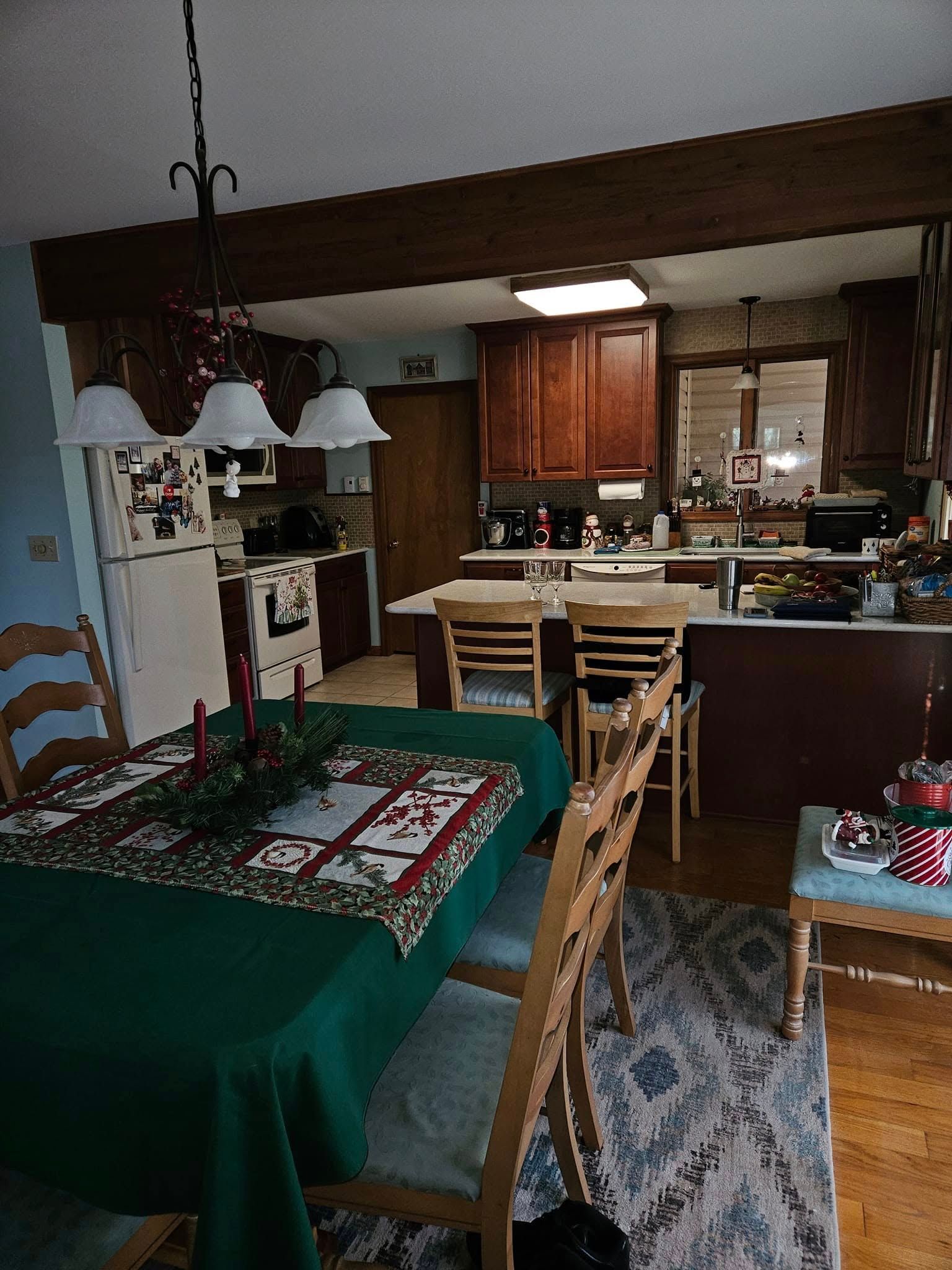 Dining room view into a kitchen with wooden cabinets, a table with chairs, and hanging pendant lights.