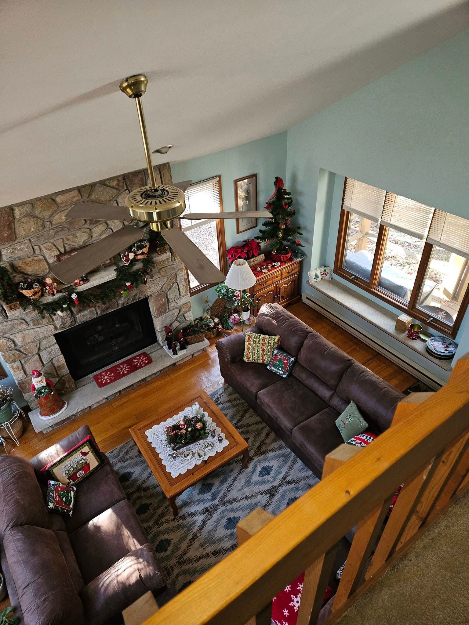 Living room with a sectional sofa, fireplace, coffee table, ceiling fan, and Christmas decorations