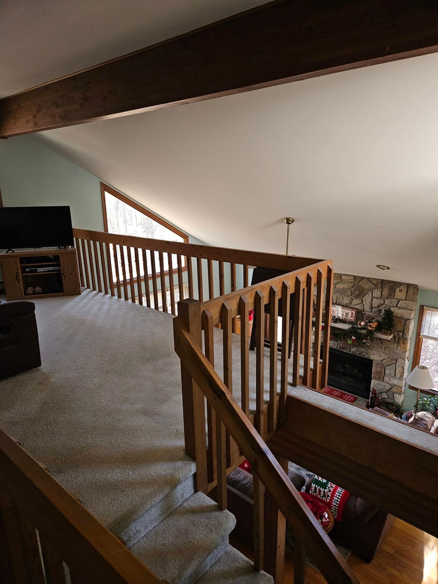 Loft landing with carpet, wooden railing, and view down to a living room below.