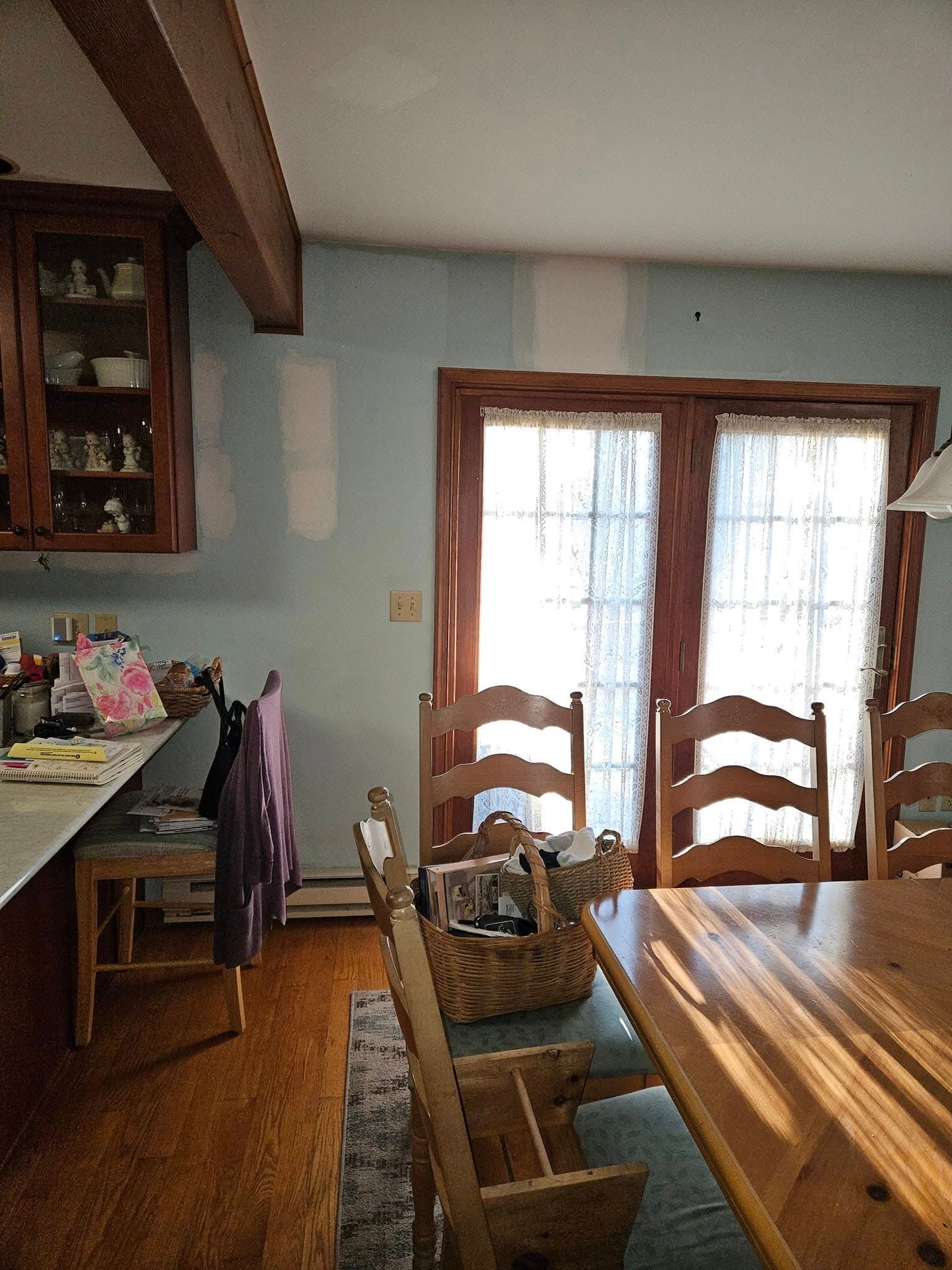 Dining room with wooden table and chairs, French doors, and a small desk by the wall.