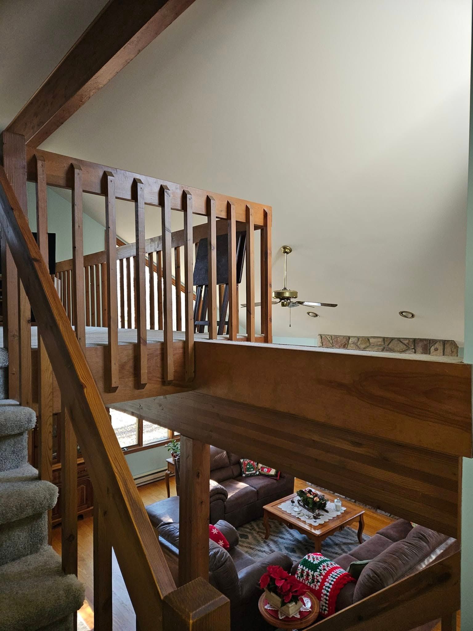 Loft view of a living room with wooden railings, exposed beams, and a couch below.