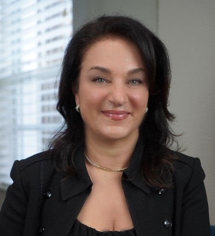 A woman in a black jacket is smiling for the camera