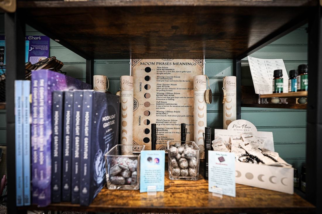 Books, crystals, and moon-themed items on wooden shelves in a store.
