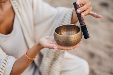 A woman is holding a singing bowl in her hands.