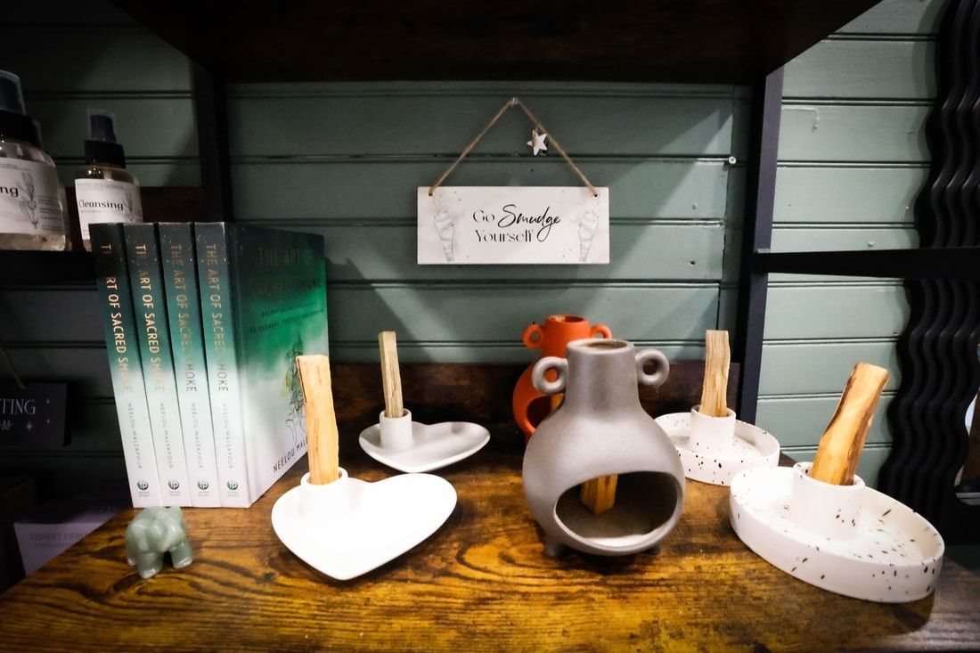 Shelf display: ceramics, books, and decorative sign against a green-paneled wall.