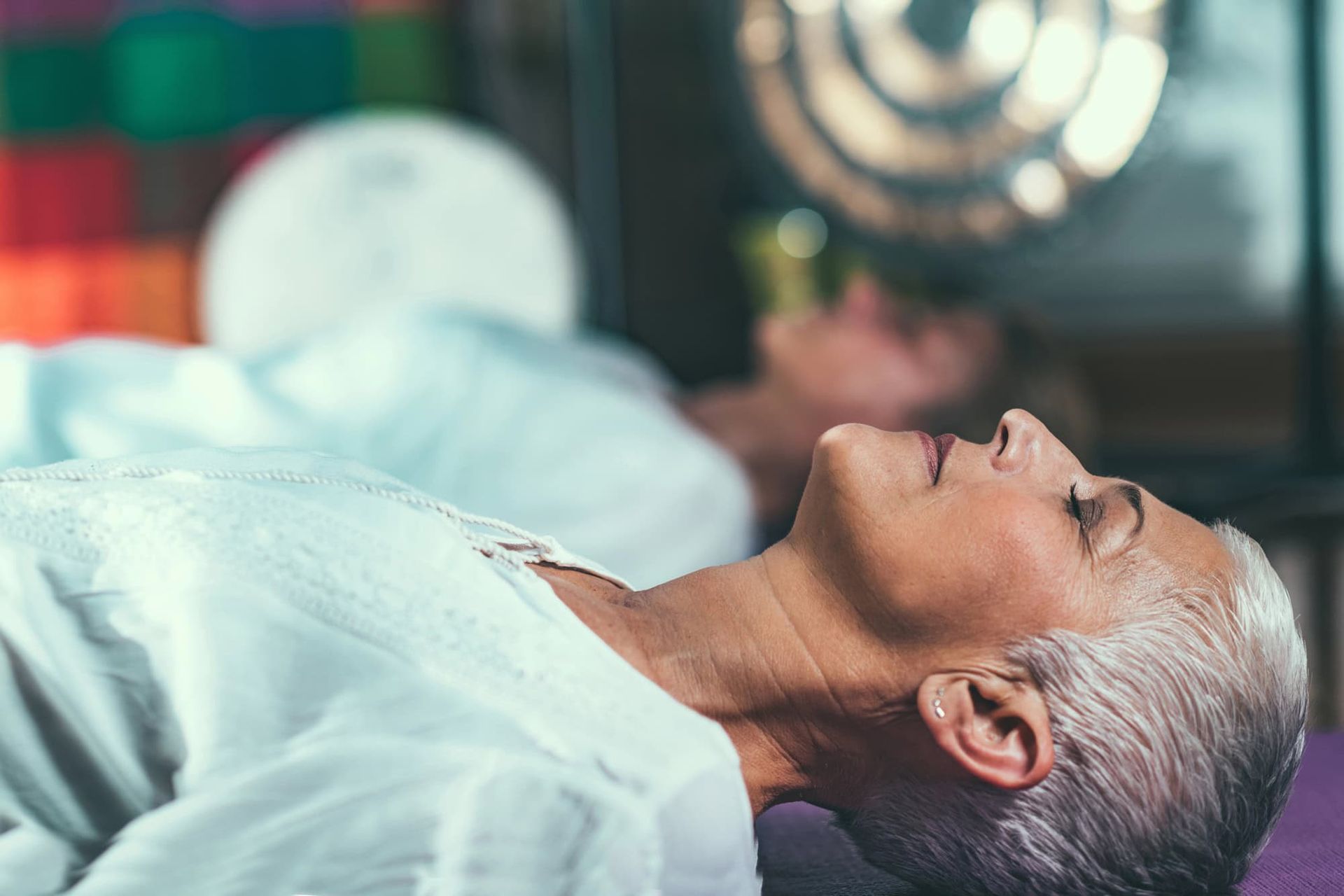 A woman is laying on a yoga mat with her eyes closed.